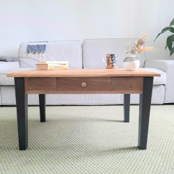Table basse unique avec piètement noir fusain, plateau en bois restauré, vue d’ensemble dans un salon.