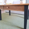 Détail des pieds en bois peints en noir fusain et du tiroir, montrant la solidité et le raffinement de la table basse.