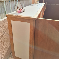 Vue de coté du buffet avec une porte ouverte. Panneau de coté blanc craie réhaussé par la chaleur du chêne.